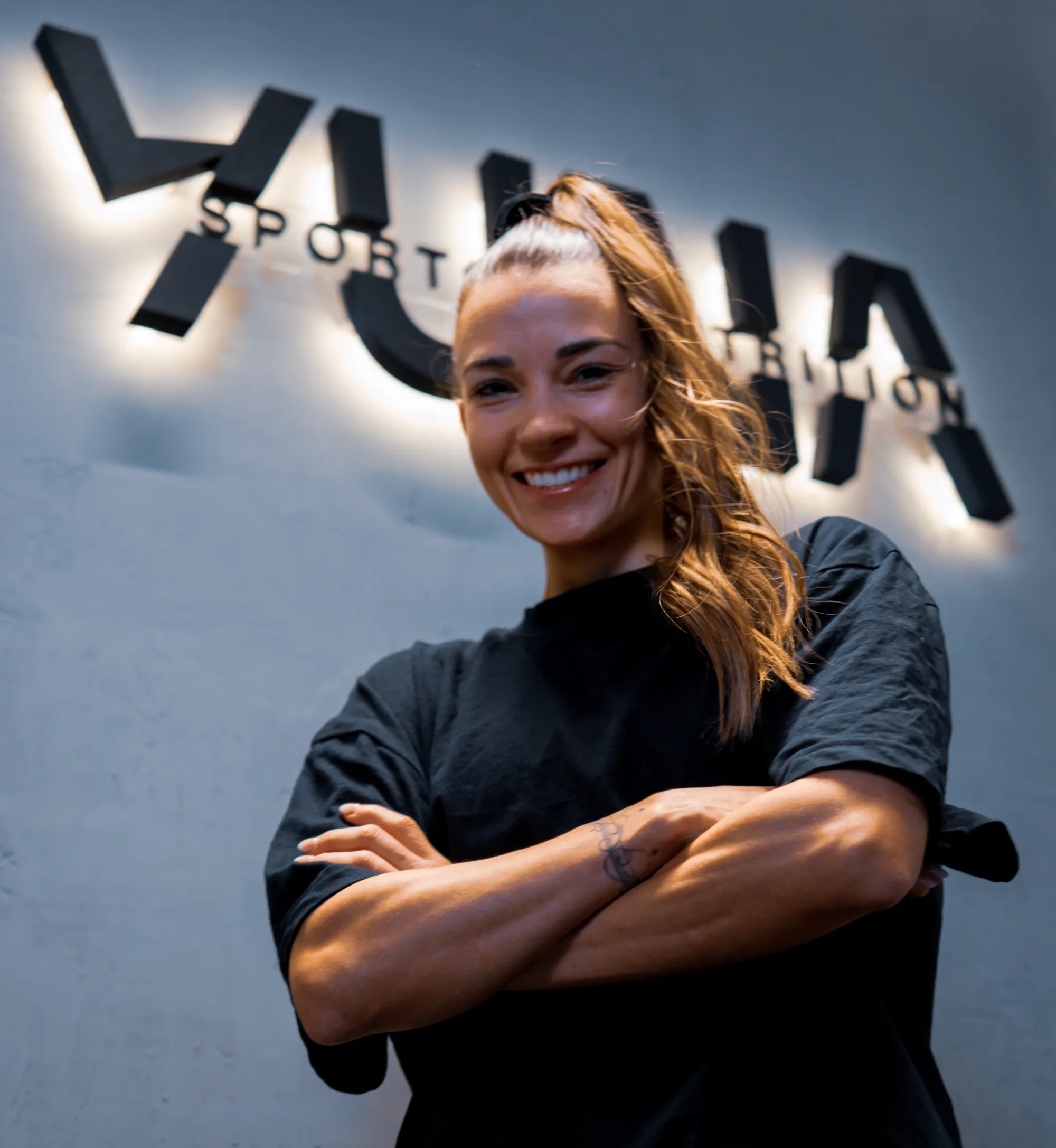 Martina Rölli, Gründerin von YUNA Sports & Nutrition, vor dem beleuchteten YUNA-Schriftzug